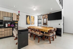 Una cocina moderna con comedor, que cuenta con una isla grande, armarios de madera y un televisor de pantalla plana montado en la pared.