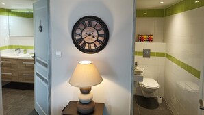 Un baño con un reloj en la pared, una lámpara de noche y un inodoro.