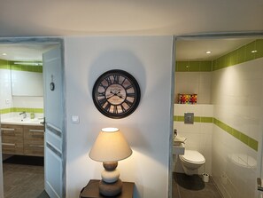 Une salle de bain avec une horloge murale, une lampe de chevet et des toilettes.