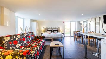 Una habitación de hotel moderna con cama, sofá, comedor y cocina.