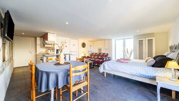 A modern interior with a dining area, kitchen, and a bedroom with a bed and bedside table.