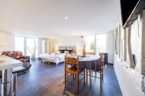 A spacious room with a bed, a dining table with chairs, and a sofa.