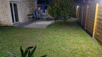 A backyard with a patio area, a wooden fence, and a small tree.
