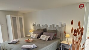 Un dormitorio con cama, almohadas, una mesita de noche con lámpara, un armario y una ventana con vistas.