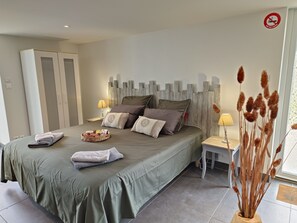 Une chambre à coucher avec un lit, des oreillers, une table de chevet avec une lampe, une armoire et une fenêtre donnant sur un beau paysage.