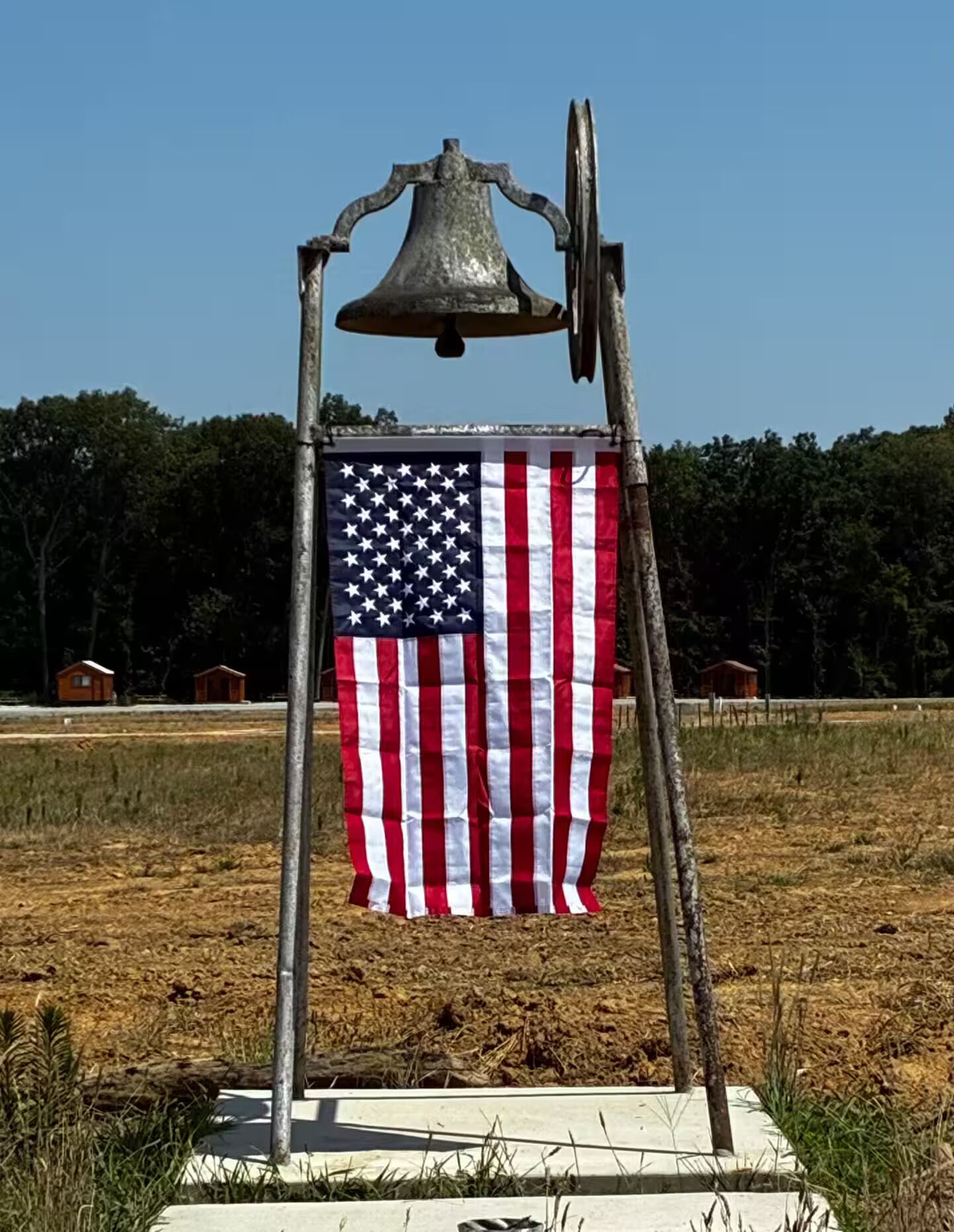 A flagpole with an American flag and a bell.