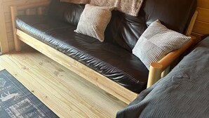 Un intérieur en bois avec un canapé en cuir, des coussins et un tapis.