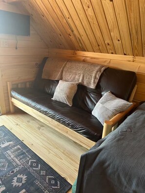 Un intérieur en bois avec un canapé en cuir, des coussins et un tapis.
