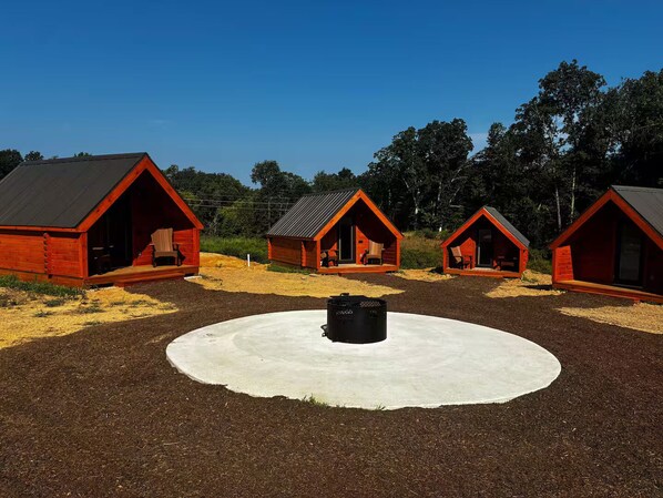 Une rangée de cabanes en bois rouges, avec une zone centrale circulaire en béton.
