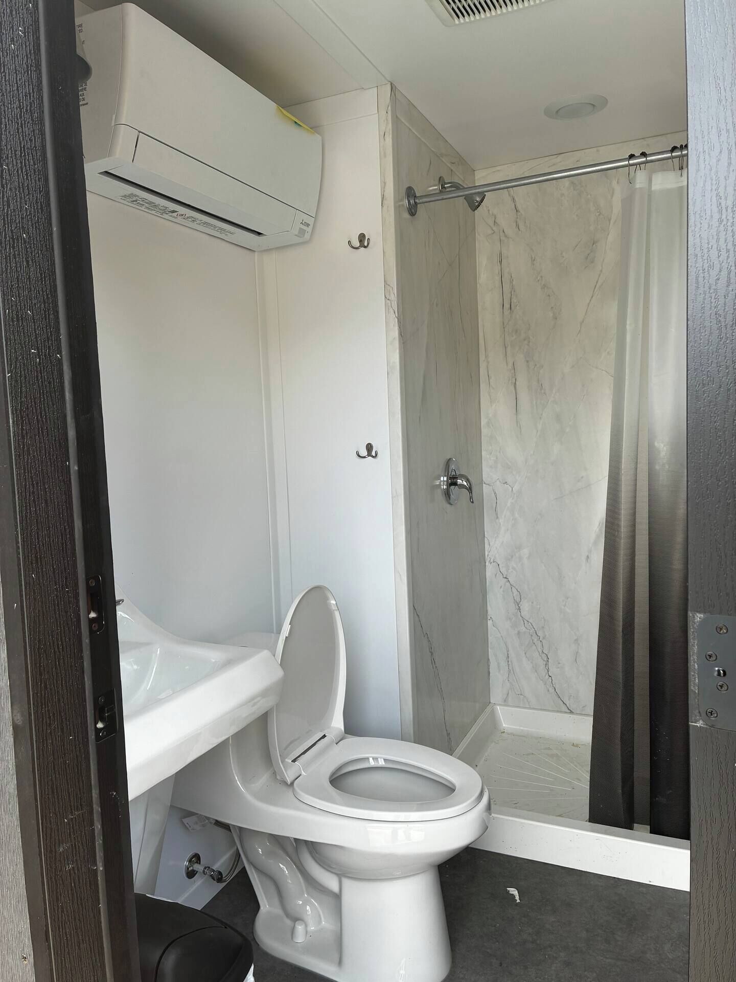 Un baño con inodoro, ducha y aire acondicionado.