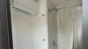 Une salle de bain équipée de toilettes, d’une douche et d’un appareil de climatisation.