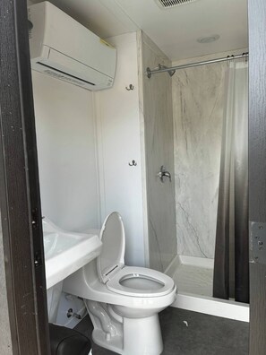 Une salle de bain équipée de toilettes, d’une douche et d’un appareil de climatisation.
