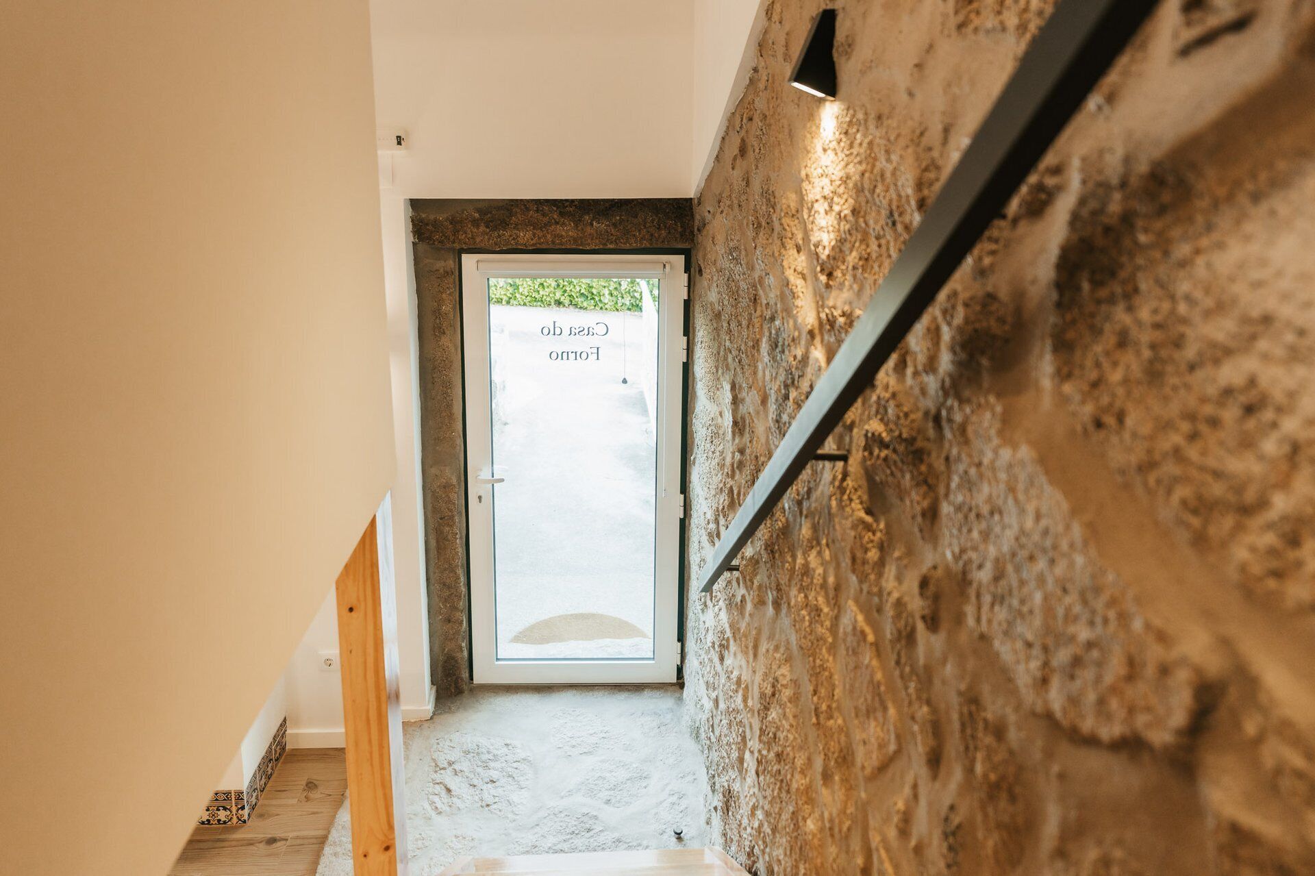 Un pasillo con pared texturizada, una puerta con panel de vidrio esmerilado y piso de madera.