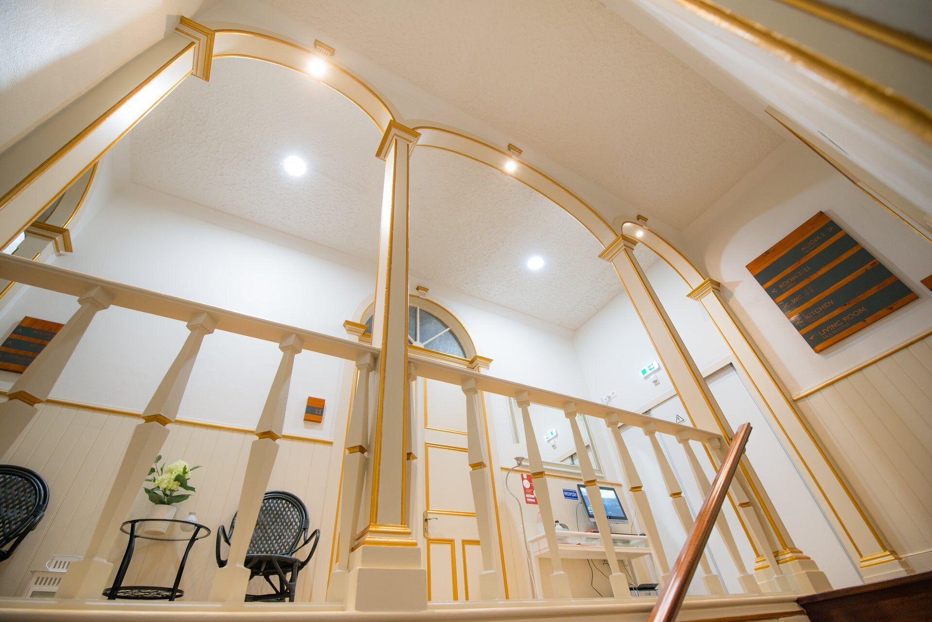 Een hotelinterieur met een receptiebalie, een zithoek en een trap met een leuning.