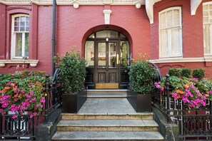 A red brick building with a black door and steps leading to the entrance. - A Grand Victorian Mansion Apartment in Marylebone (London)
