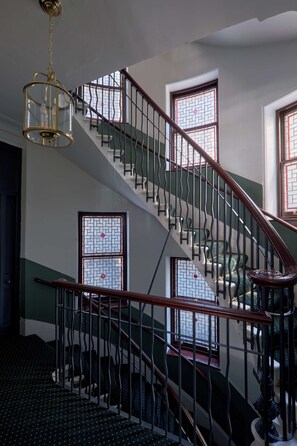 Eine Treppe mit Metallgeländer, einem Chandelier und fensterartigen Verzierungen.