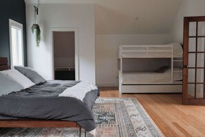 Ein Schlafzimmer mit einem Bett, einem Etagenbett, einer hängenden Pflanze und einem gemusterten Teppich.