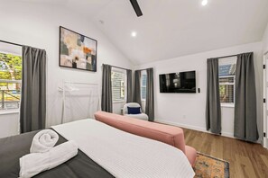A modern hotel room with a bed, a seating area, a TV, and a painting on the wall. - Cozy Chic House Pet-Friendly  Sleeps 12 (Georgetown)