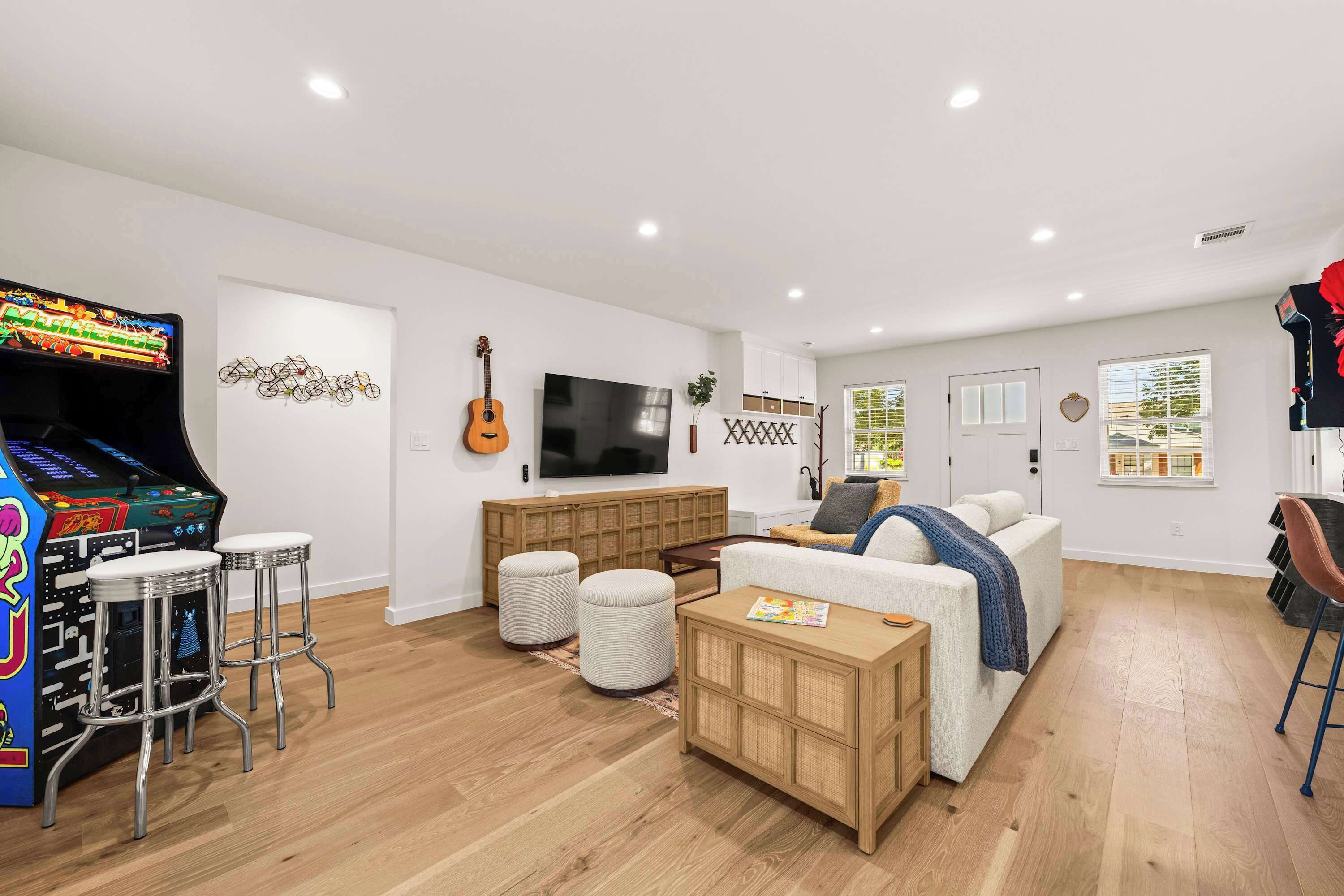 A living room with a gaming console, a TV, a guitar, and a sofa.