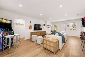 A living room with a gaming console, a TV, a guitar, and a sofa. - Cozy Chic House Pet-Friendly  Sleeps 12 (Georgetown)