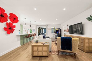 A modern living room with a sofa, coffee table, and a TV mounted on the wall. - Cozy Chic House Pet-Friendly  Sleeps 12 (Georgetown)