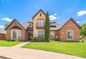 A two-story house with a stone facade, a central entrance, and a well-maintained lawn.