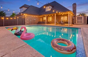 Ein Garten mit Schwimmbecken, aufblasbaren Flamingos und einem Donut-Badeartikel.