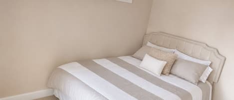 Un dormitorio con una cama, una ventana con persianas y piso alfombrado.