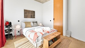 A modern bedroom with a bed, bedside table, lamp, and a wooden bench. - GuestReady - House of Many Faces - Room 2 (Porto)