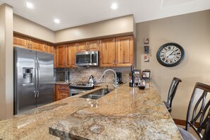 A modern kitchen with stainless steel appliances, granite countertops, and wooden cabinets. - Crystal Peak Lodge 7008 ~ Ski-in/Ski-out ~ NEW LISTING ~ By CoralTree Residences (Breckenridge)