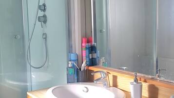 Ett badrum med en duschkabin i glas, två handfat och en stor spegel.