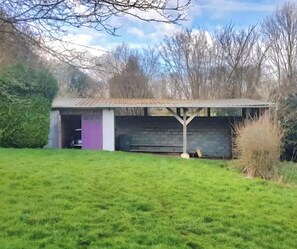 Un petit bâtiment d’un seul étage, doté d’un toit en pente, d’une porte violette et d’une zone clôturée à l’avant.