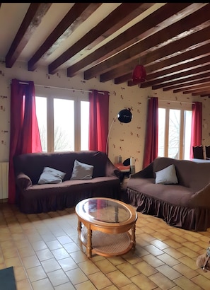 A living room with two sofas, a round wooden coffee table, and a red hanging lamp.