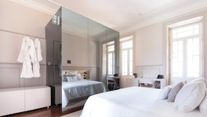 A hotel room with a large bed, a desk, a mirror, and a wardrobe.