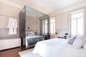 Een hotelkamer met een groot bed, een bureau, een spiegel en een kledingkast.