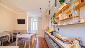 A modern kitchen with white cabinetry, wooden countertops, and a breakfast bar. There are multiple seating areas with tables and chairs, and a large window providing natural light.