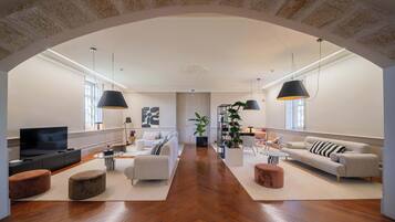 A spacious living area with a modern design, featuring a large TV, comfortable seating, and a stone arch ceiling.