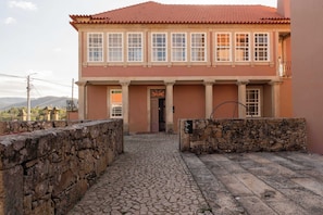 Un bâtiment avec un toit recouvert de tuiles rouges, des murs en pierre et une cour pavée.