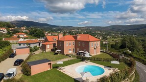 A large house with a swimming pool, surrounded by a well-maintained lawn and a view of the countryside.