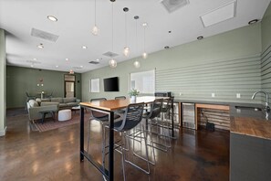 A modern kitchen with a bar area, a dining table, and a seating area with a sofa and chairs. - Luxury Loft + King Bed Heart of Downtown STL (St. Louis)