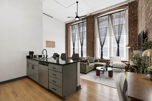 A modern kitchen with a central island, a dining area with a round table, and a seating area with a sofa and armchairs. - Luxury Loft + King Bed Heart of Downtown STL (St. Louis)