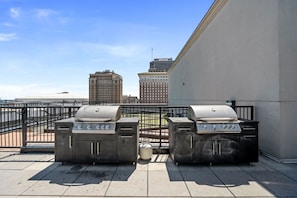 Two barbecue grills on a rooftop terrace with a city skyline in the background. - Luxury Loft + King Bed Heart of Downtown STL (St. Louis)
