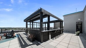 A rooftop terrace with a covered seating area, a bar, and a view of the city skyline.