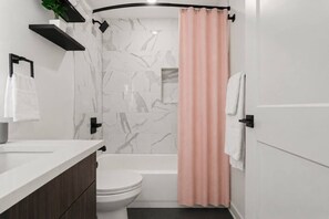 Ein modernes Badezimmer mit Toilette, Waschbecken und Duschbereich.