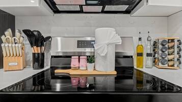 A modern kitchen with a stainless steel stove, a knife block, pepper and salt shakers, a towel, and a spice rack.