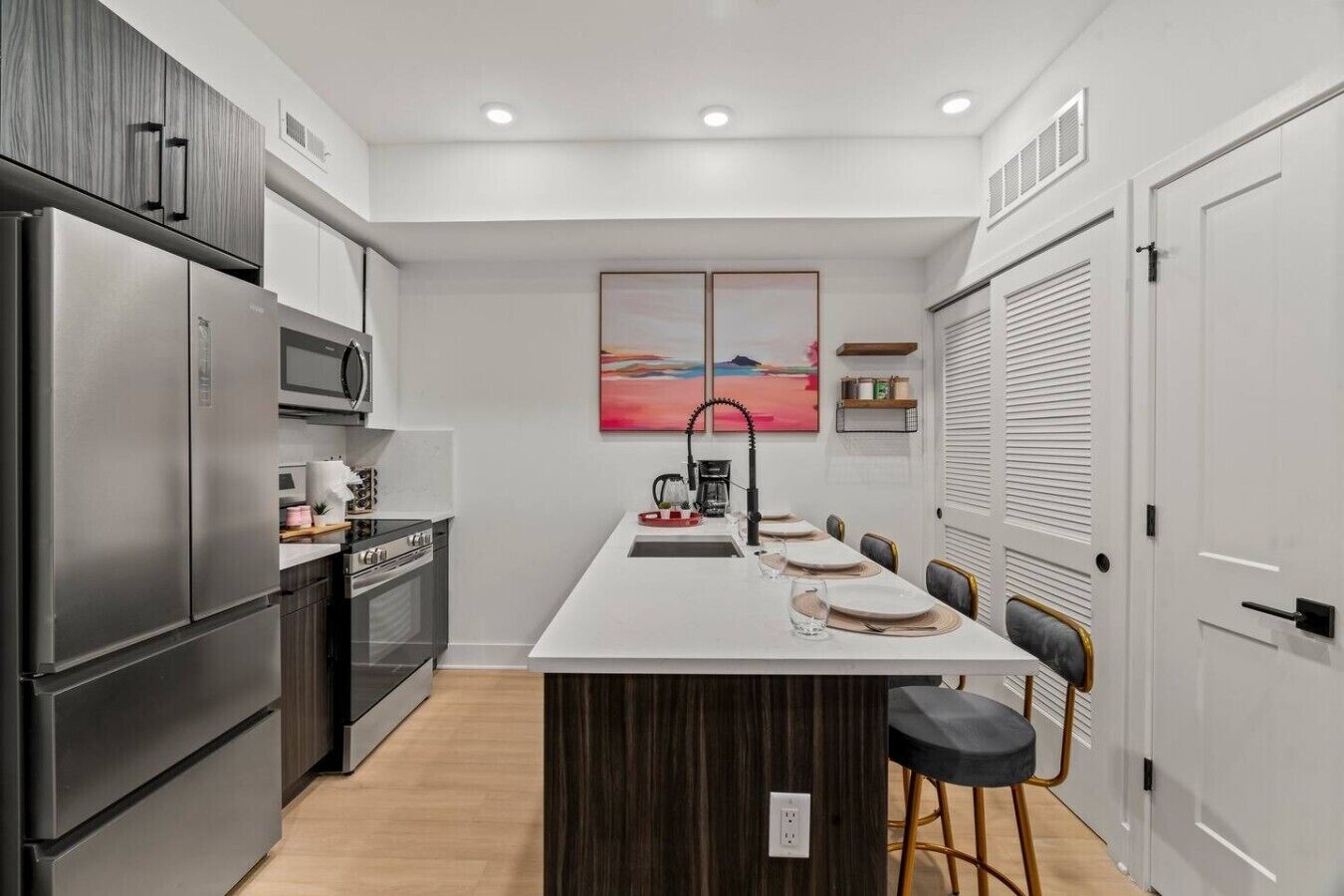 A modern kitchen with a central island, stainless steel appliances, and a dining area with chairs.