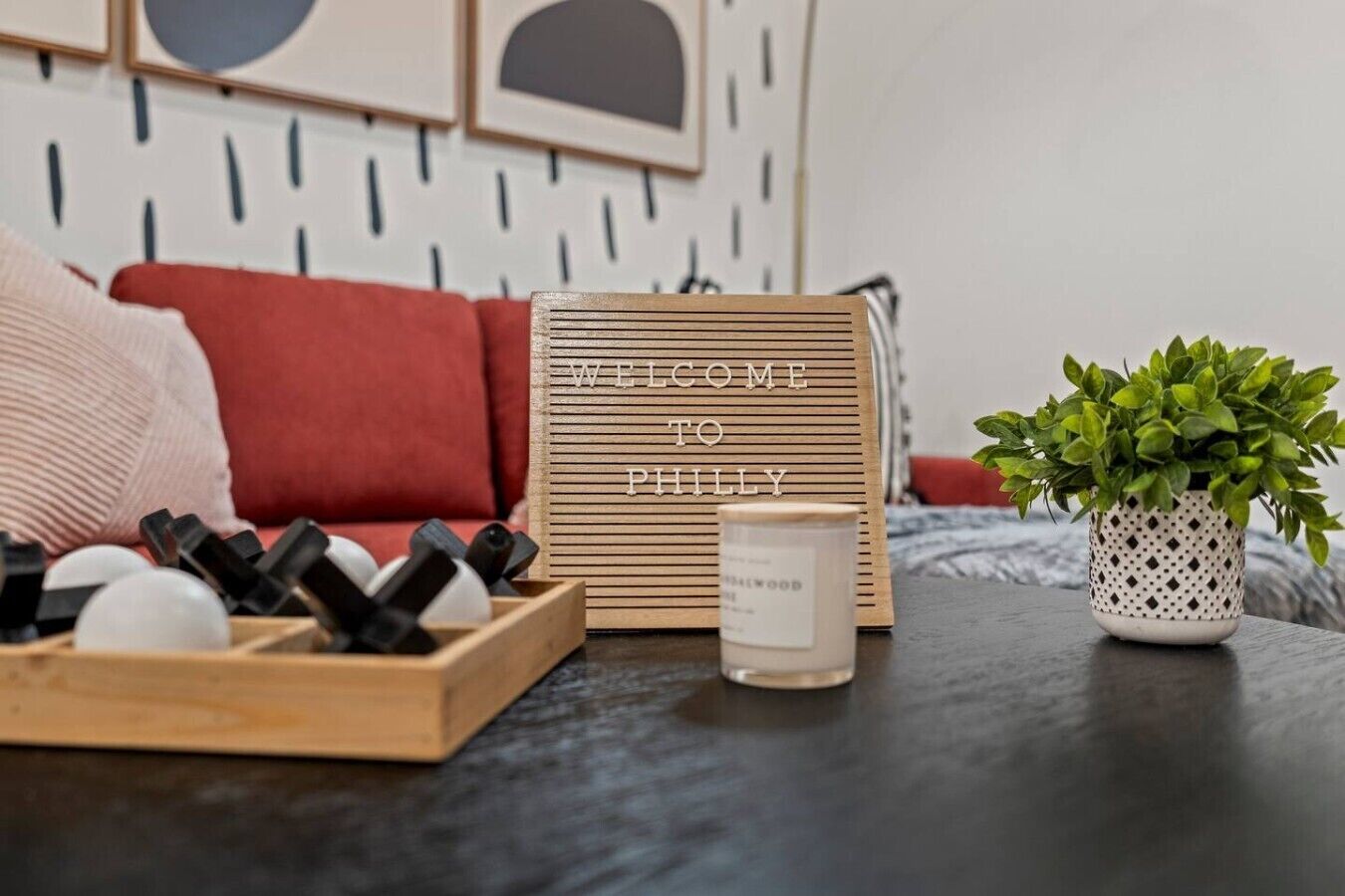 A wooden welcome sign, a candle, and a potted plant on a table.