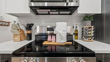 A modern kitchen with a stainless steel stove, a microwave above, and a knife block on the counter.