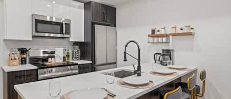 A modern kitchen with a central island, built-in appliances, and bar stools.