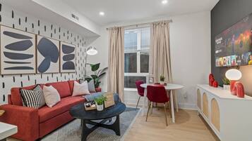 A modern living room with a red sofa, a coffee table, and a dining area with a white table and red chairs.